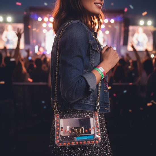 Woman with a clear crossbody purse at a concert with blurred crowd and stage lights in the background