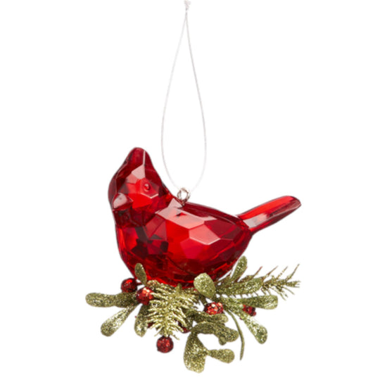 Red glass cardinal bird ornament with greenery on a white background