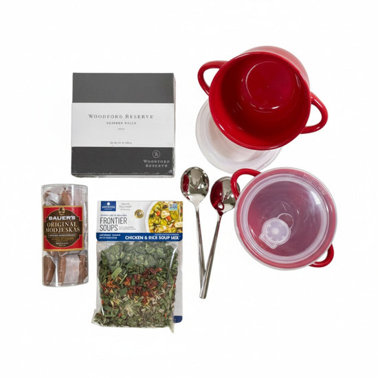 Top-down view of the gift basket contents: two bowls, spoons, soup mix, Modjeskas, and bourbon balls.