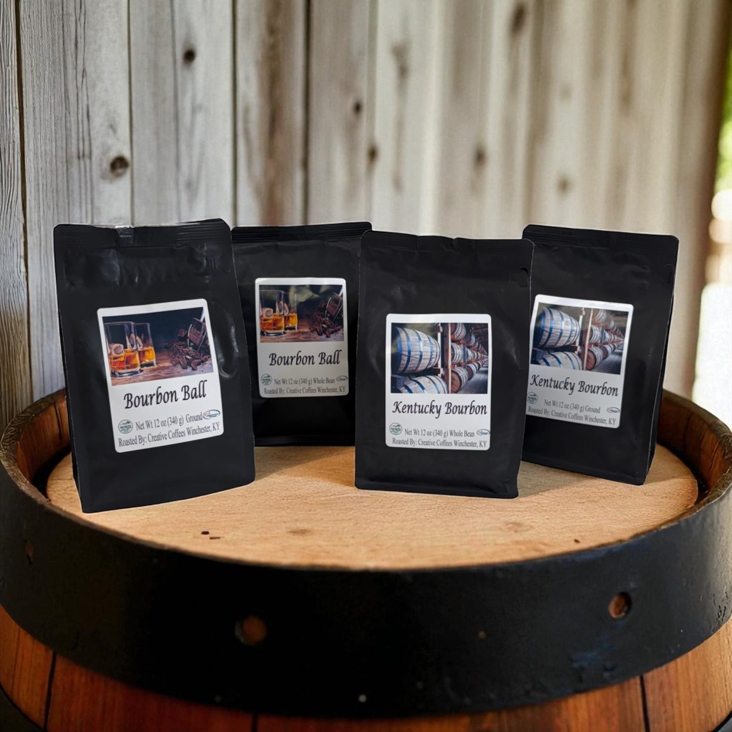 Four black coffee bags with labels on a wooden barrel against a wooden background