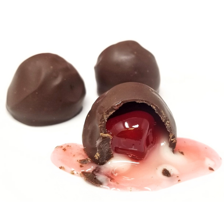 Chocolate covered cherry with white chocolate drizzle on a white background