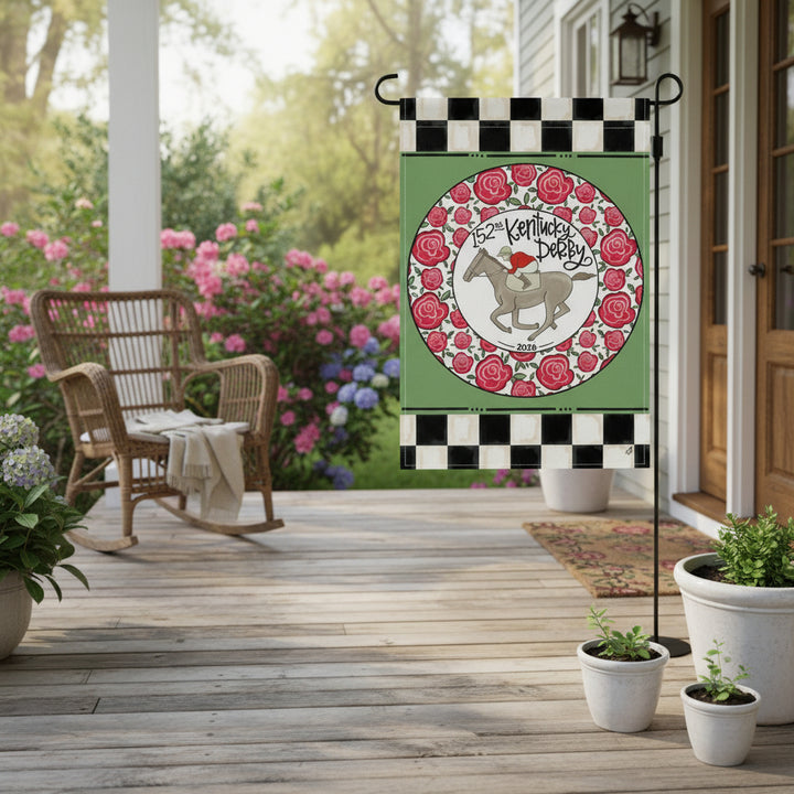 The Ring of Roses garden flag hanging on a charming porch, surrounded by potted plants and creating a festive atmosphere.