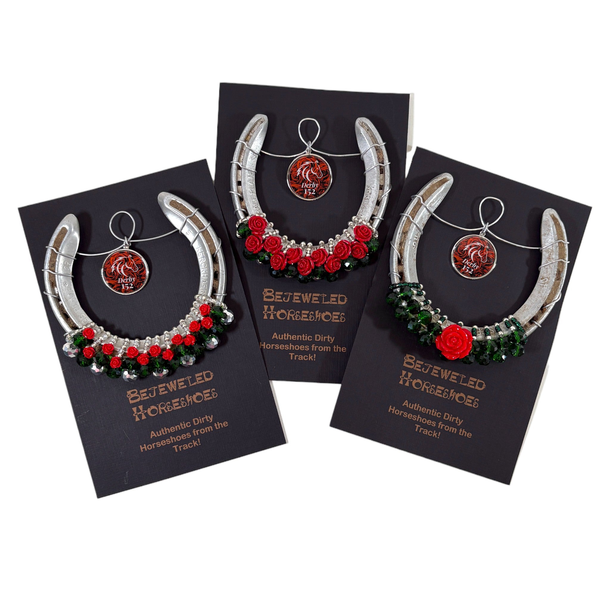 Three jeweled horseshoe ornaments on black cards with visible branding.