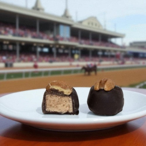 Chocolate-covered bourbon balls on a plate with a blurred stadium background