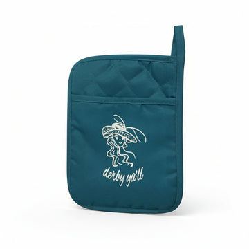 Close-up of a teal pot holder featuring a white embroidered design of a woman in a large hat with the text "derby y'all."