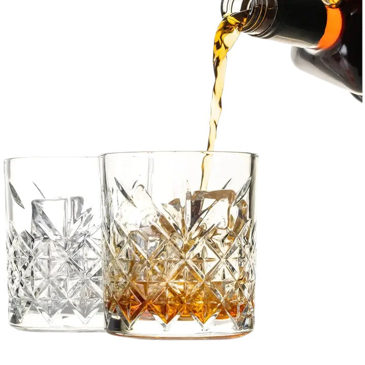 Whiskey pouring into a diamond-cut rocks glass with ice.