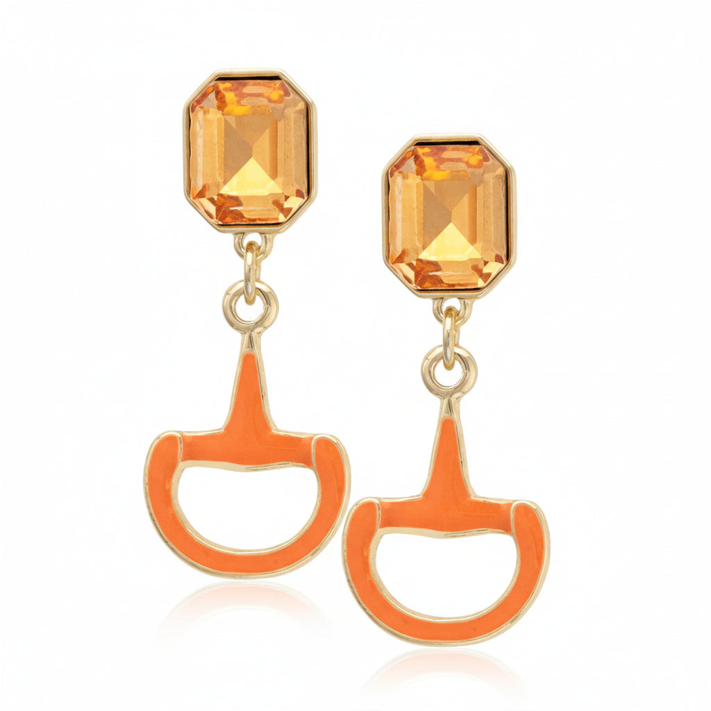 Close-up of the orange Eclipse Horsebit Earring, highlighting the sparkling rhinestone details and gold-tone finish.