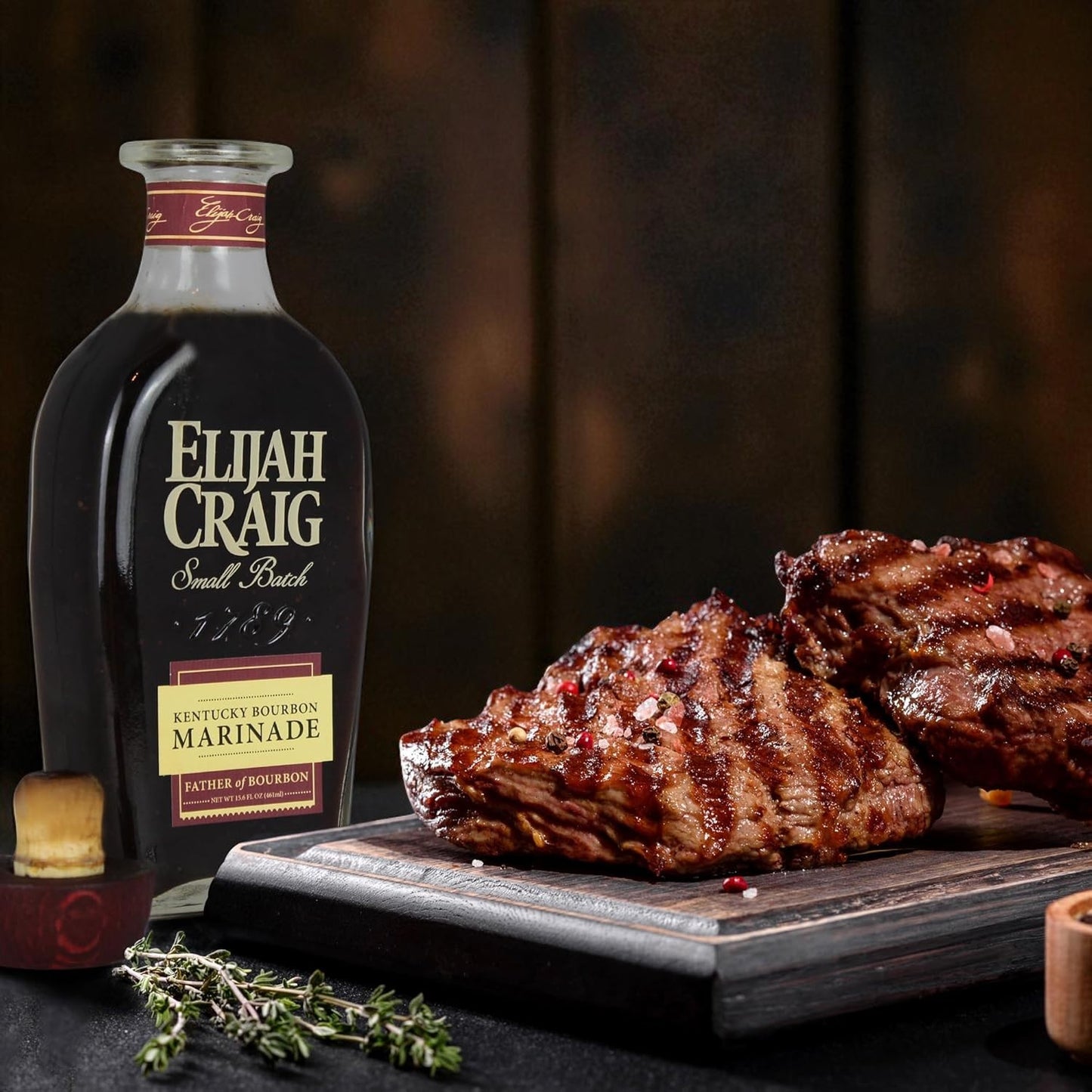 Bottle of Elijah Craig bourbon marinade with marinated meat on a wooden board.