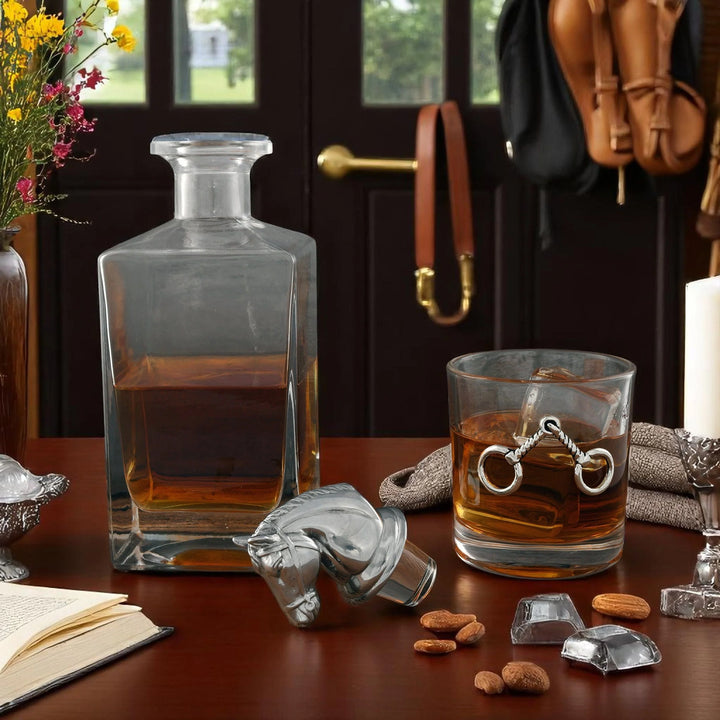 Glass decanter and glass with liquid on a table with decorative items.