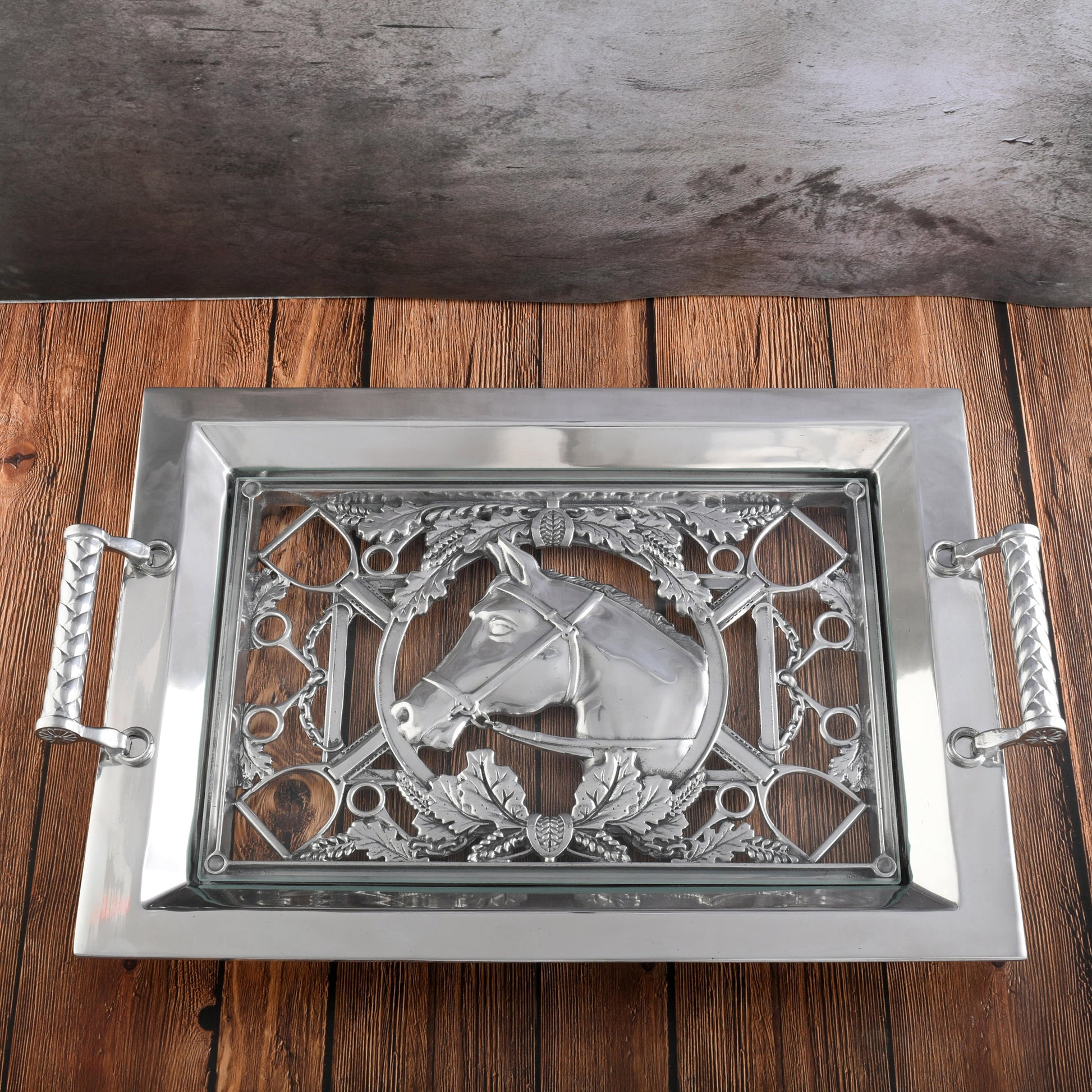 Decorative silver tray with horse design on a wooden surface