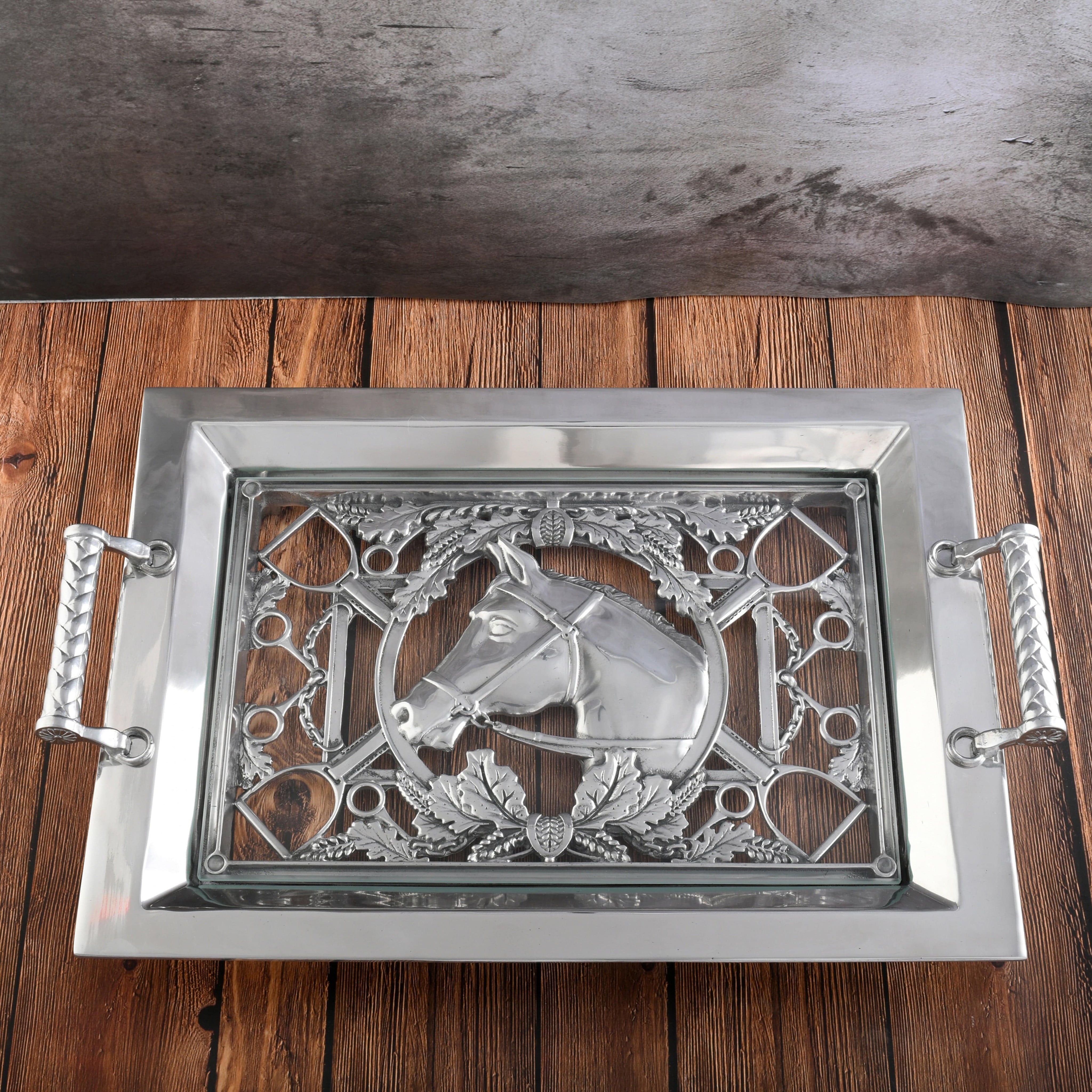 Decorative silver tray with horse design on a wooden surface