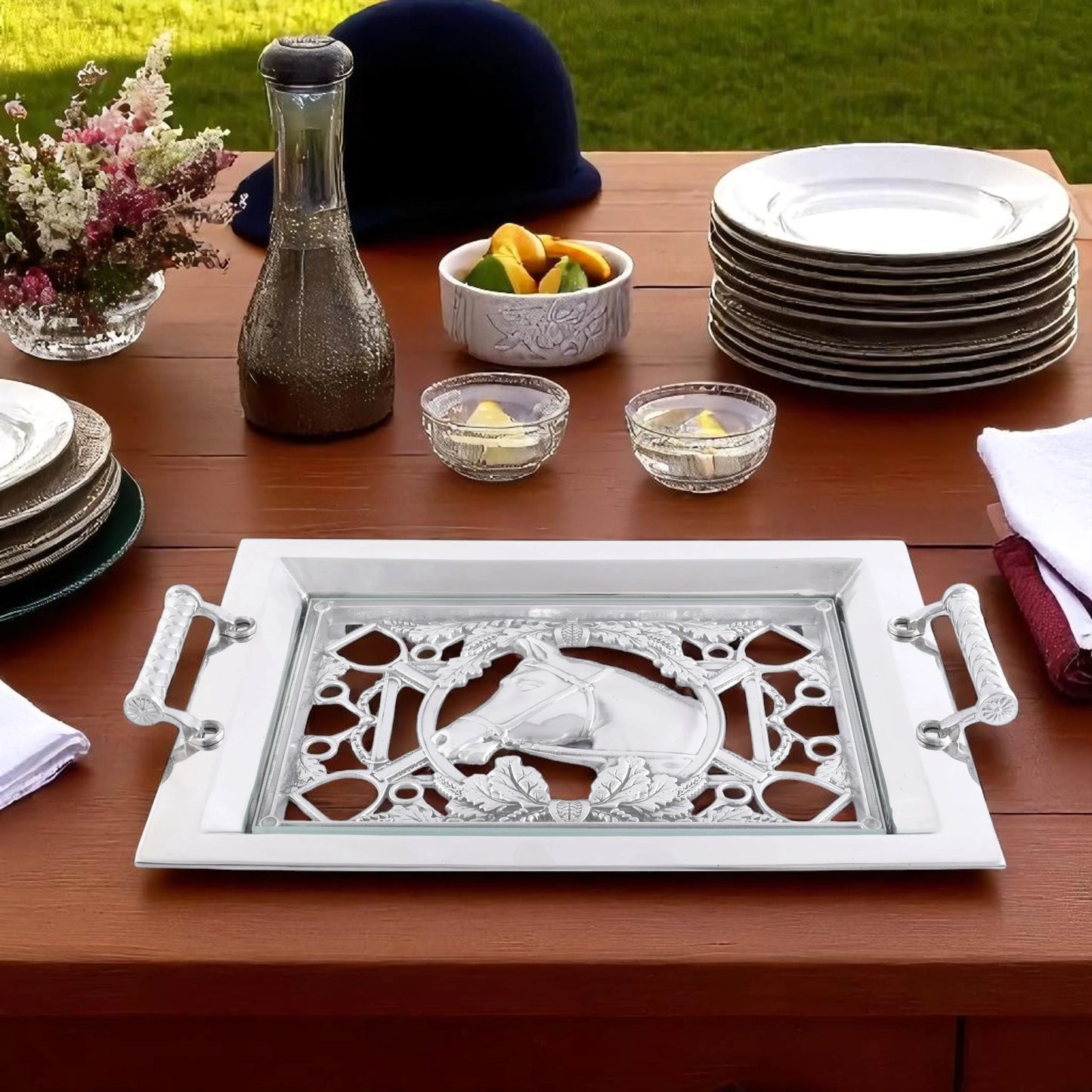 Decorative tray with intricate design on a wooden table with plates and other items.