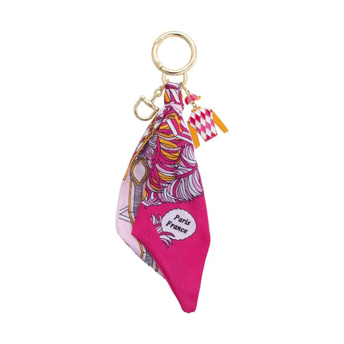 A flat lay image of the Fiona Jockey Scarf Bag Charm, showing the hand-knotted pink and orange fabric and the gold-tone horsebit ring.