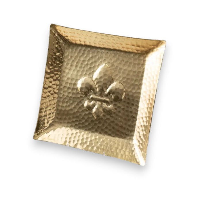 A sophisticated 12-inch square decorative plate made of textured hammered aluminum, featuring a prominent, raised three-dimensional fleur-de-lis emblem in the center.