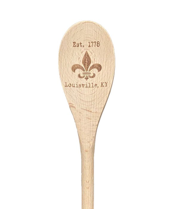 Wooden spoon with engraved fleur de lis and text on a white background