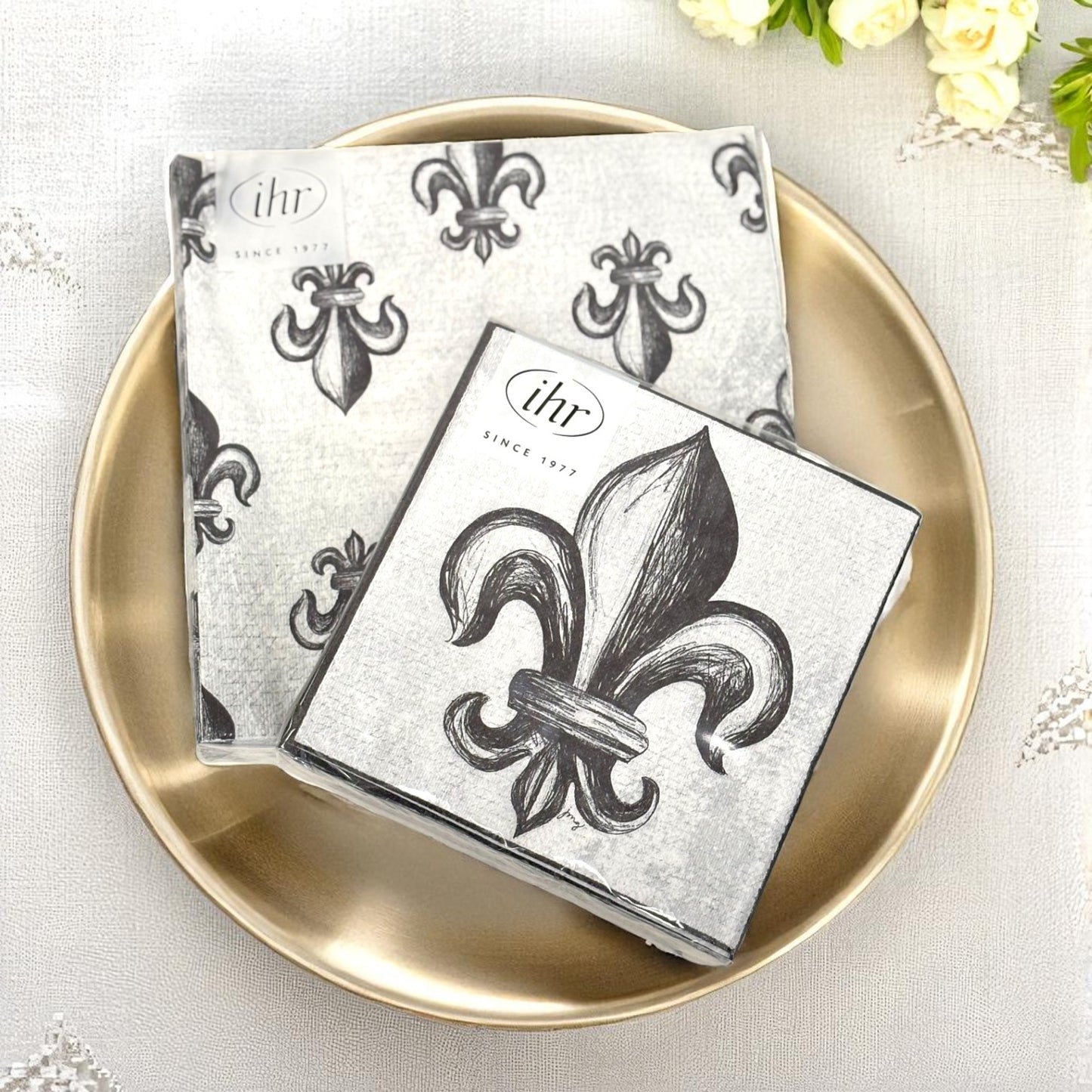 An elegant table setting featuring the Fleur-de-Lis napkins paired with a gold charger and glassware for a party.