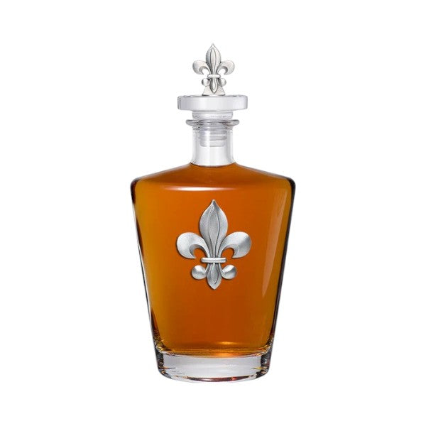 Glass decanter with silver fleur-de-lis design on a white background