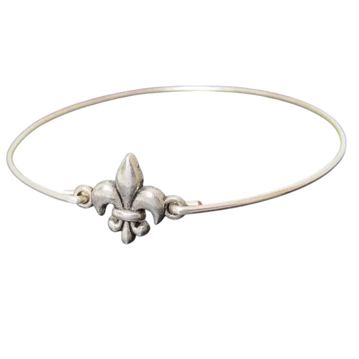 A delicate silver-filled bangle bracelet with a central fleur de lis charm on a white background.
