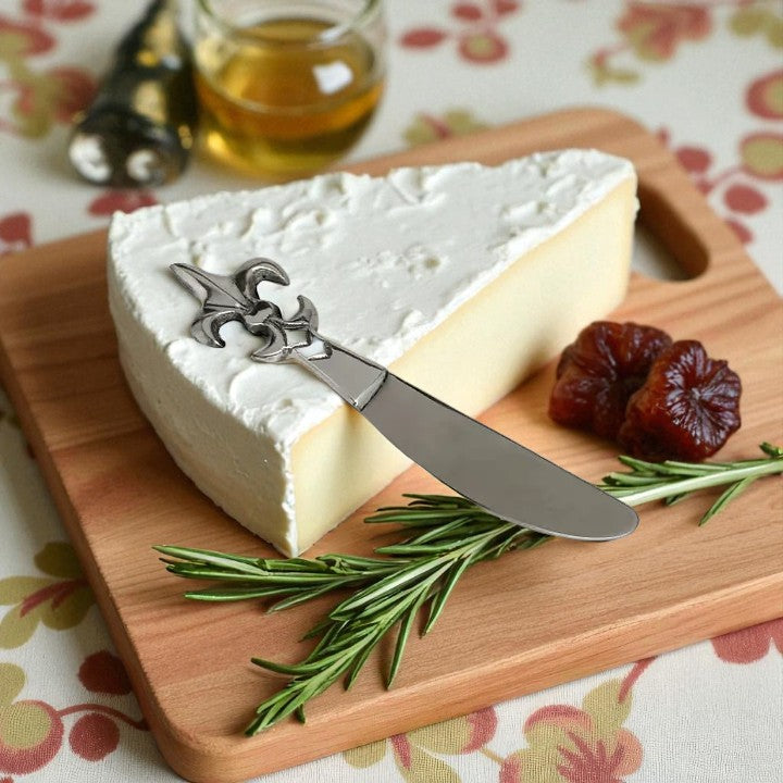 Cheese with a knife on a wooden board with herbs and dates, on a floral tablecloth.