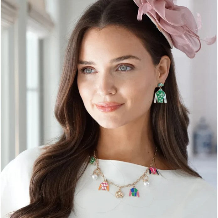 A model wearing the Freckles Jockey Silk Enamel Drop Earrings, adding a festive splash of color to her look.