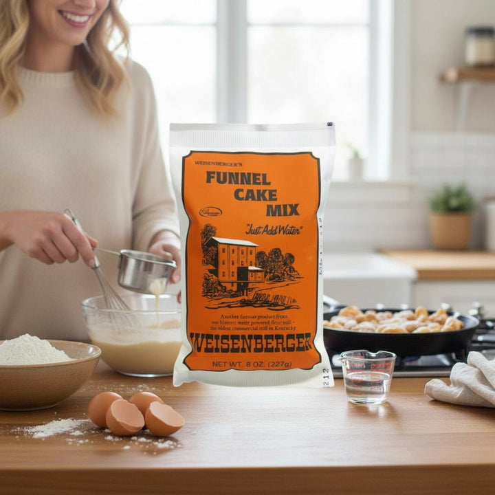 Funnel cake batter being drizzled from a measuring cup into hot oil.