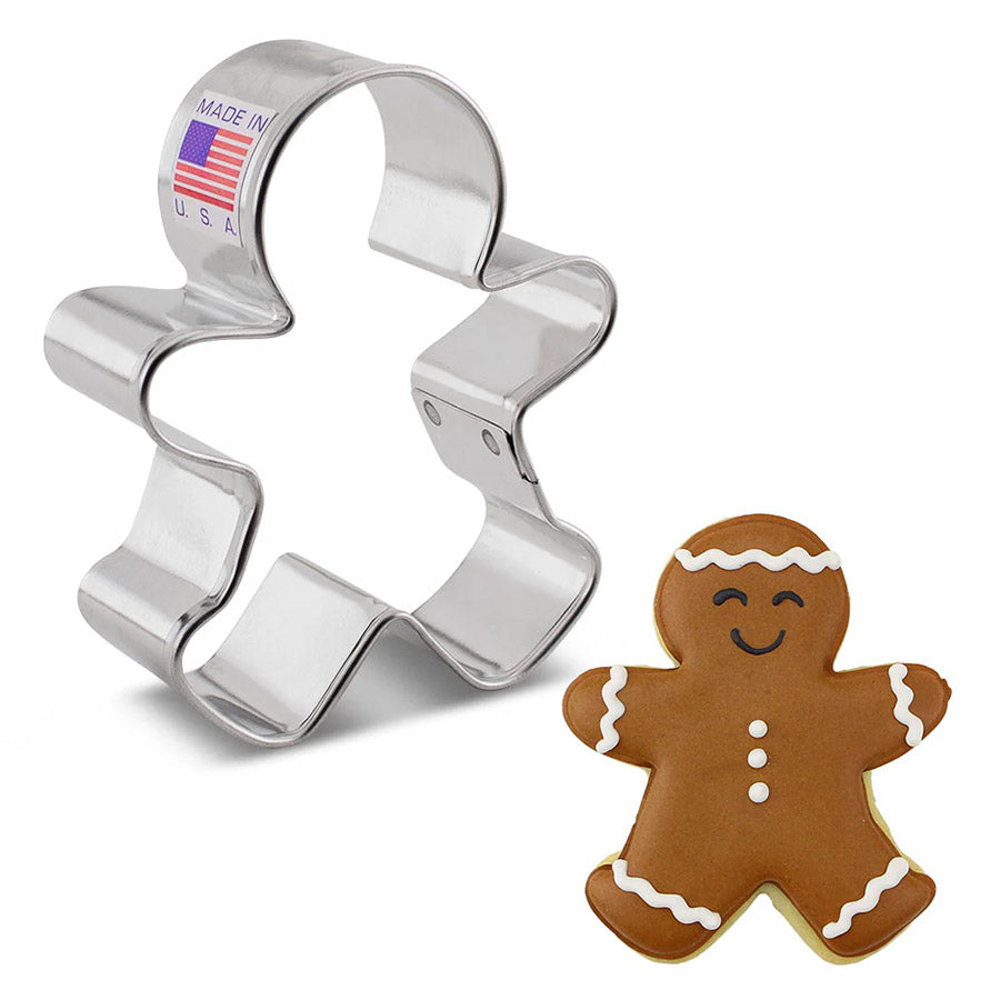 Metallic gingerbread man cookie cutter with a gingerbread man cookie on a white background