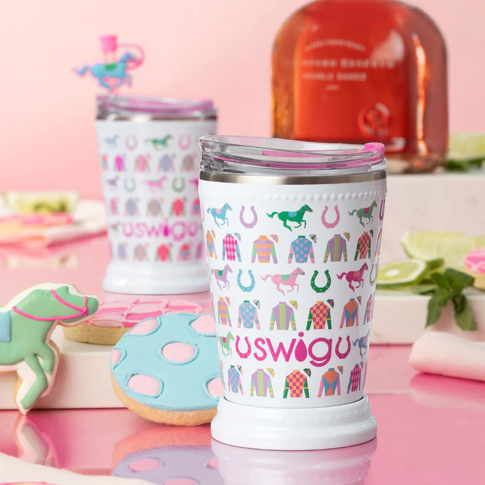 The 12oz Mint Julep cup in the Go Baby Go pattern and 'swigg' branding on a pink background with cookies and a bottle.