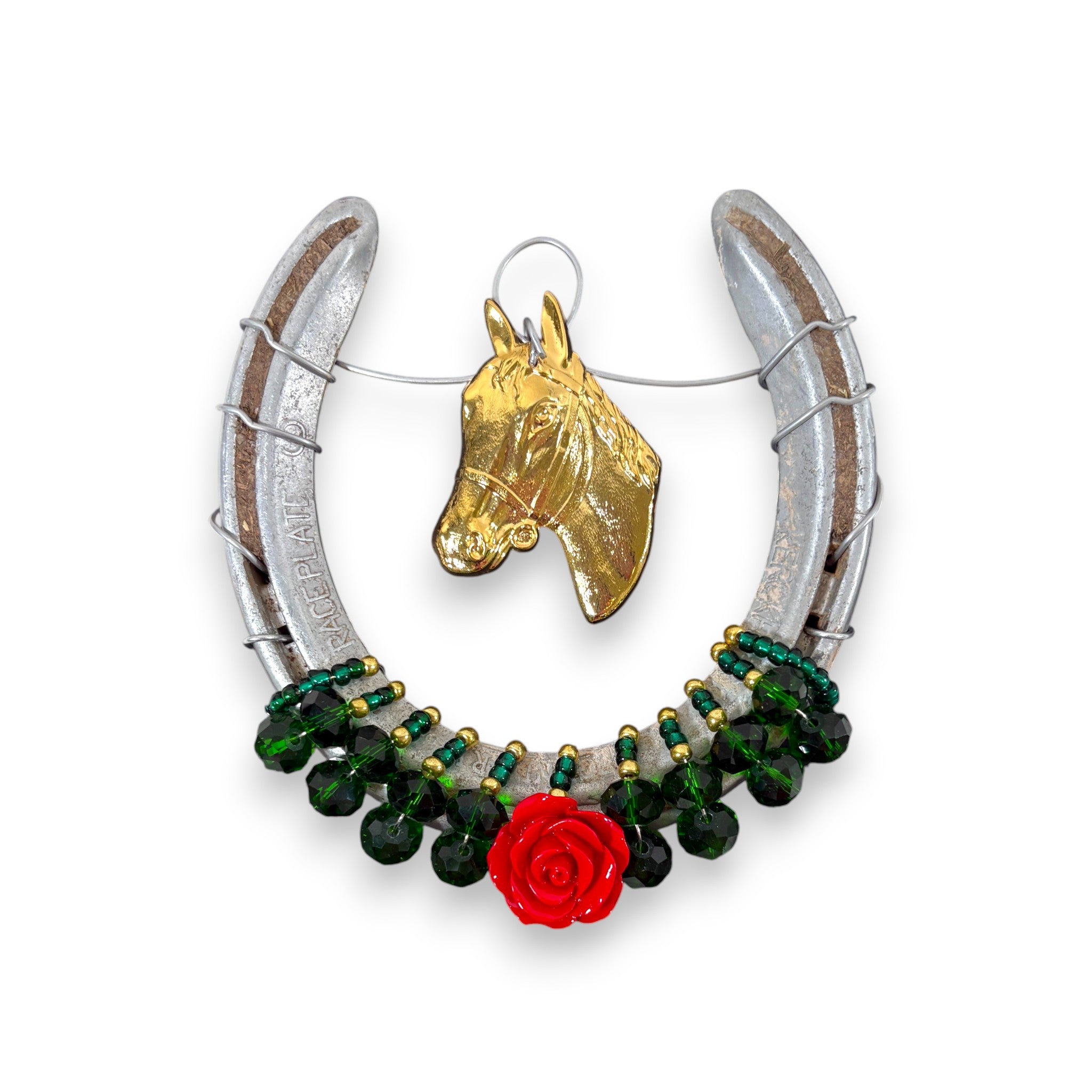 A close-up of the bejeweled horseshoe featuring a gold horsehead charm and a single red rose.