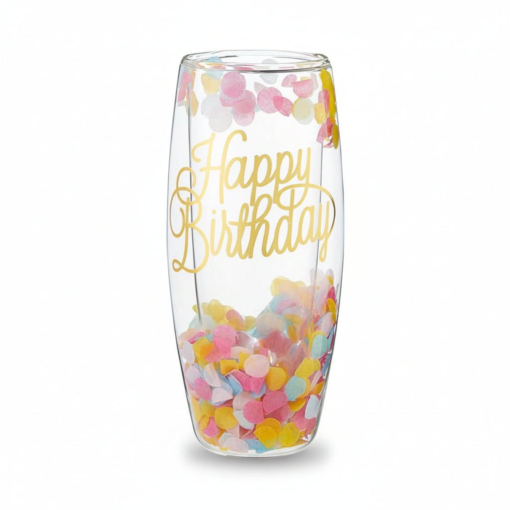 A clear, stemless double-wall champagne glass filled with colorful pastel confetti and featuring "Happy Birthday" in gold script.