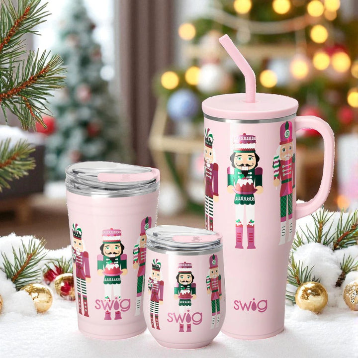 Set of pink Swig tumblers with Sugar Plum nutcracker design in a festive setting.