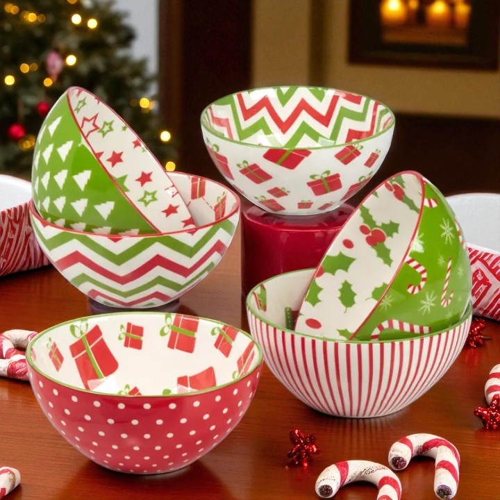 Set of Christmas-themed ceramic bowls on a wooden surface with festive decorations.