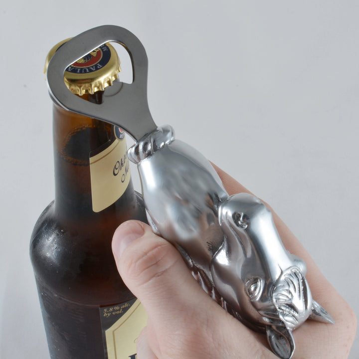 Metal bottle opener shaped like a dog being used on a bottle.