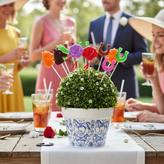 Decorative topiary with A colorful assortment of handcrafted Derby lollipops in horse head, red rose, and horseshoe shapes on a table with people in the background.