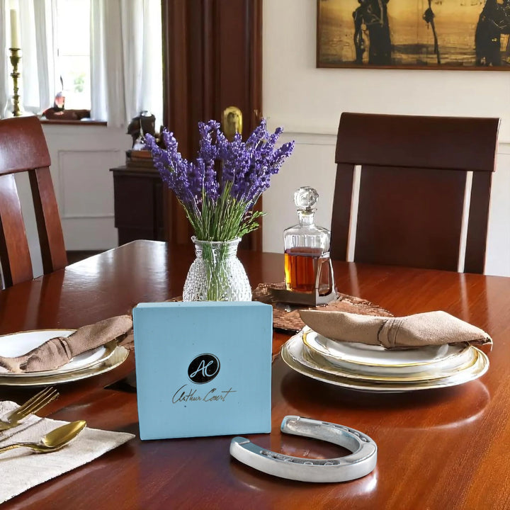 Dining table set with plates, napkins, a vase of lavender, and a decanter.