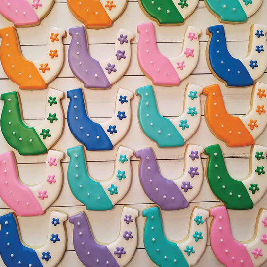 Colorful horse shoe cookies with decorative elements on a wooden surface
