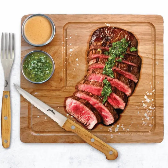 A lifestyle photo showing a delicious sliced steak served on the Jim Beam board with sauces.