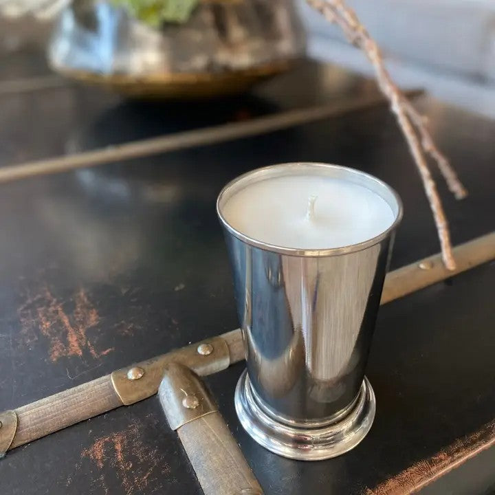 Silver candle holder with a white candle on a dark surface