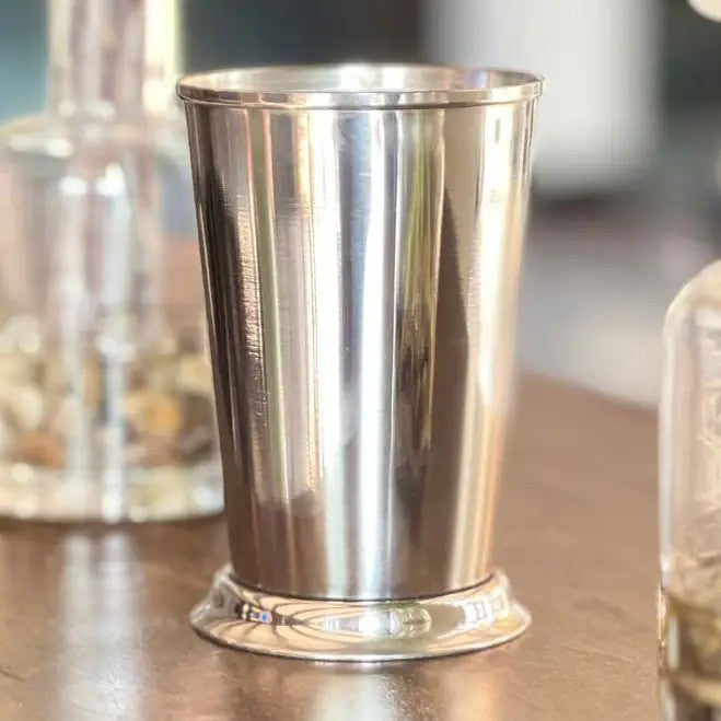 Silver metal cup on a reflective surface with blurred background