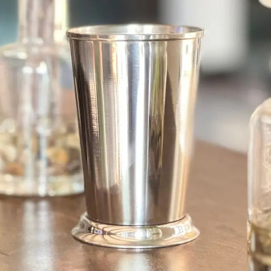 Silver metal cup on a reflective surface with blurred background