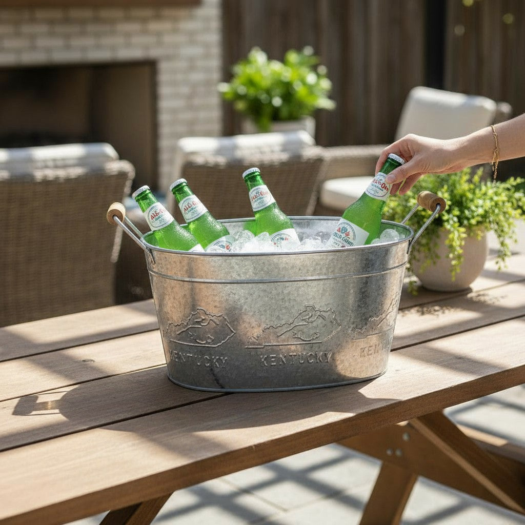 A galvanized beverage tub with an embossed Kentucky design filled with ice and bottles on a patio.