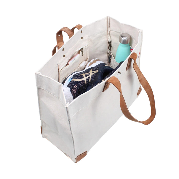  Detail shot of the bag's interior, showcasing the durable canvas, thick leather handles, and adjustable brass stud closure.