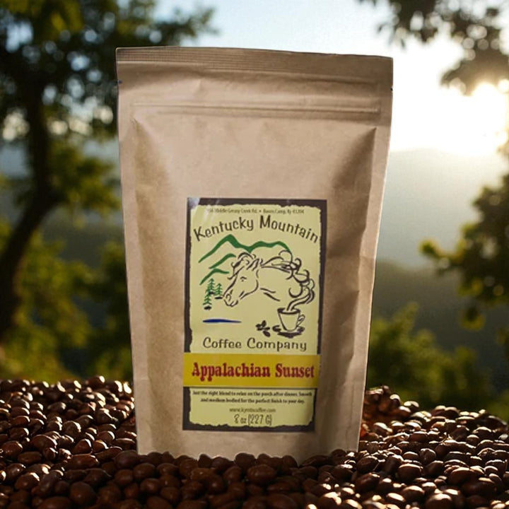Kentucky Mountain Coffee Company Appalachian Sunset coffee package on roasted coffee beans with a scenic background