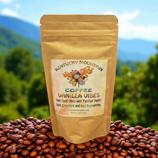 Kraft paper coffee package labeled 'Kentucky Mountain Coffee Vanilla Vibes' on a bed of coffee beans with a mountainous background.