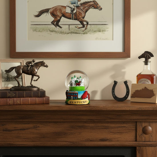 The Kentucky Snow Globe displayed on a rustic wooden mantelpiece next to other decor.