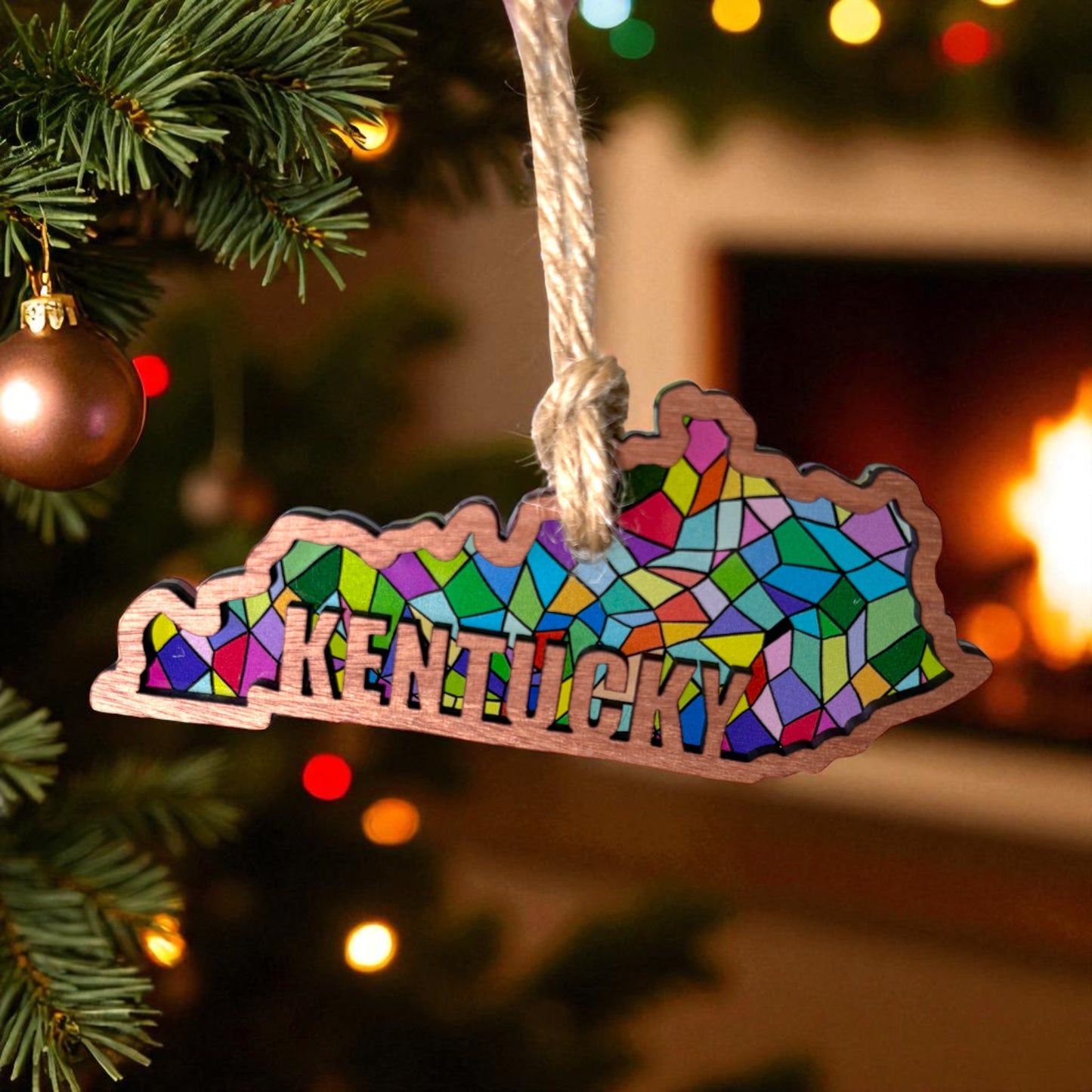 Colorful Kentucky-shaped ornament on a Christmas tree with a fireplace in the background