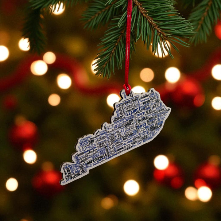 Decorative ornament shaped like a state with text, hanging on a Christmas tree.