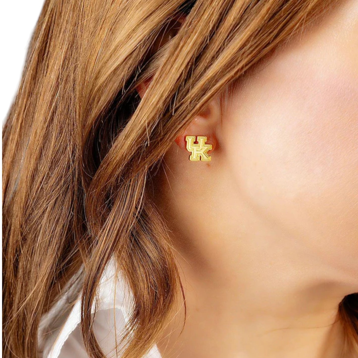 Gold earrings with 'UK' symbol worn by a person with brown hair.