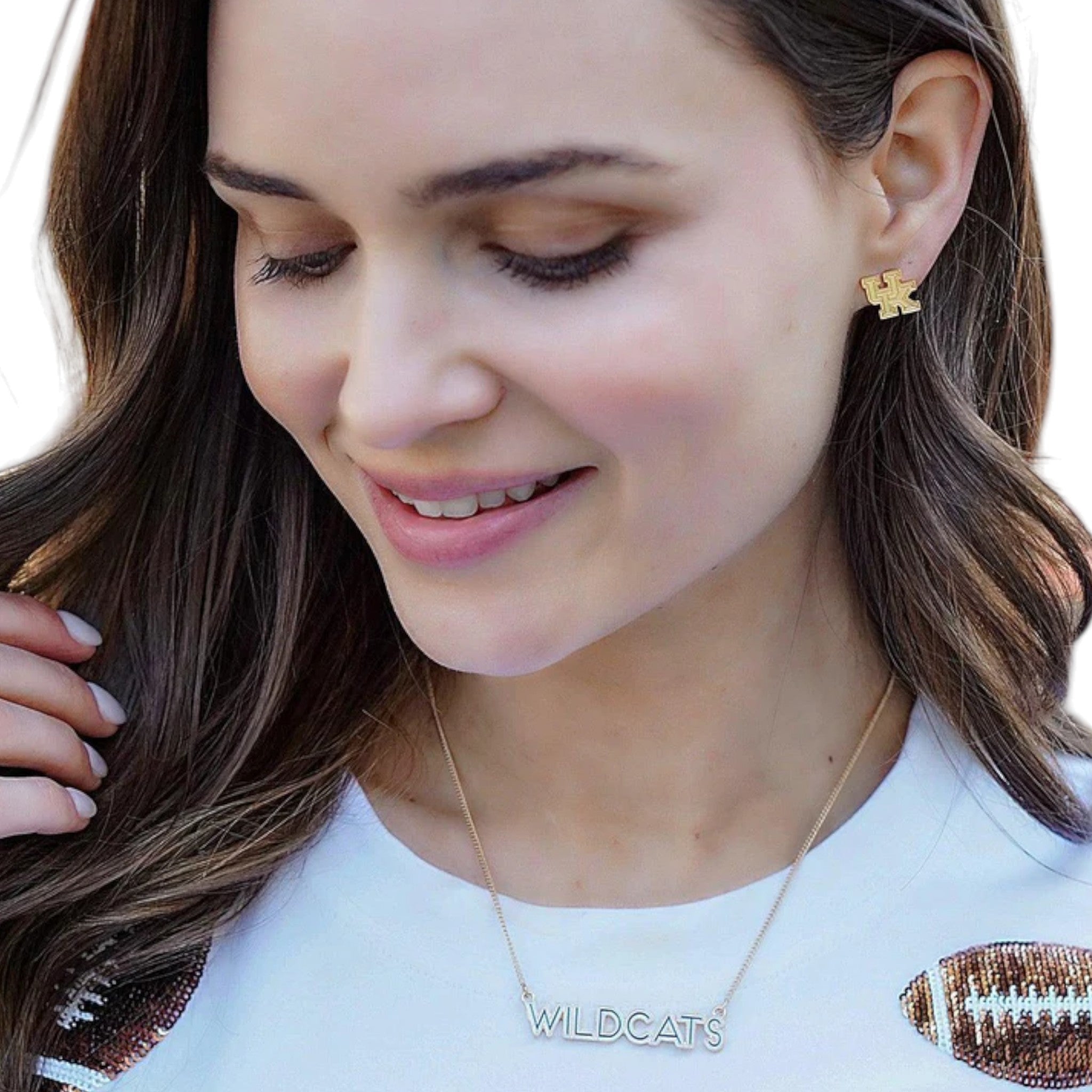 Woman wearing gold earrings and a necklace with 'WILDCATS' on a white background