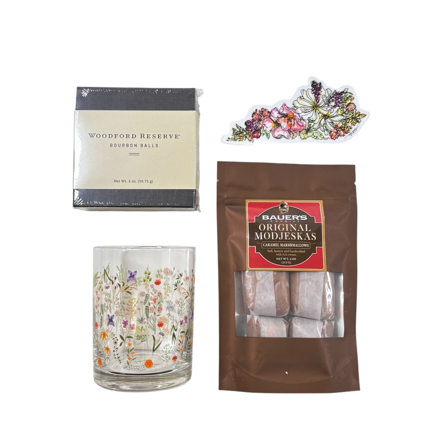 Top-down view of the gift basket contents: Boho Flower Rocks Glass, wildflower sticker, bourbon balls, and Modjeskas.