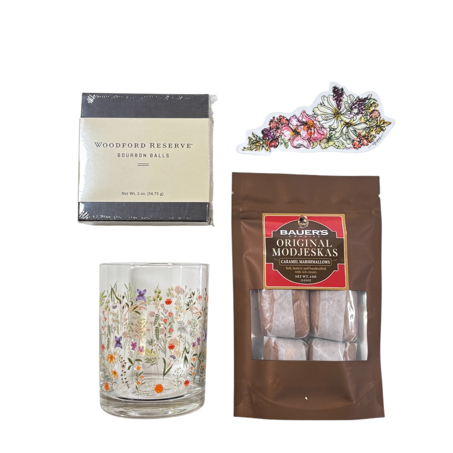 Top-down view of the gift basket contents: Boho Flower Rocks Glass, wildflower sticker, bourbon balls, and Modjeskas.
